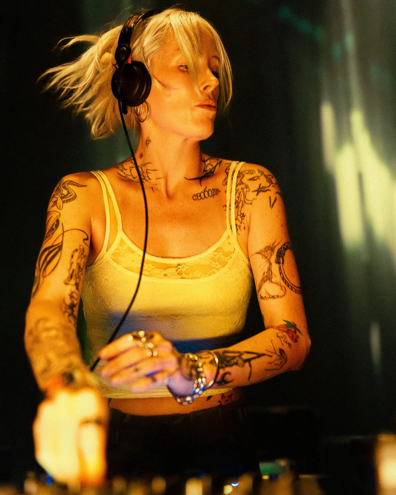 Tattooed DJ adjusting controls at the booth during a live set.