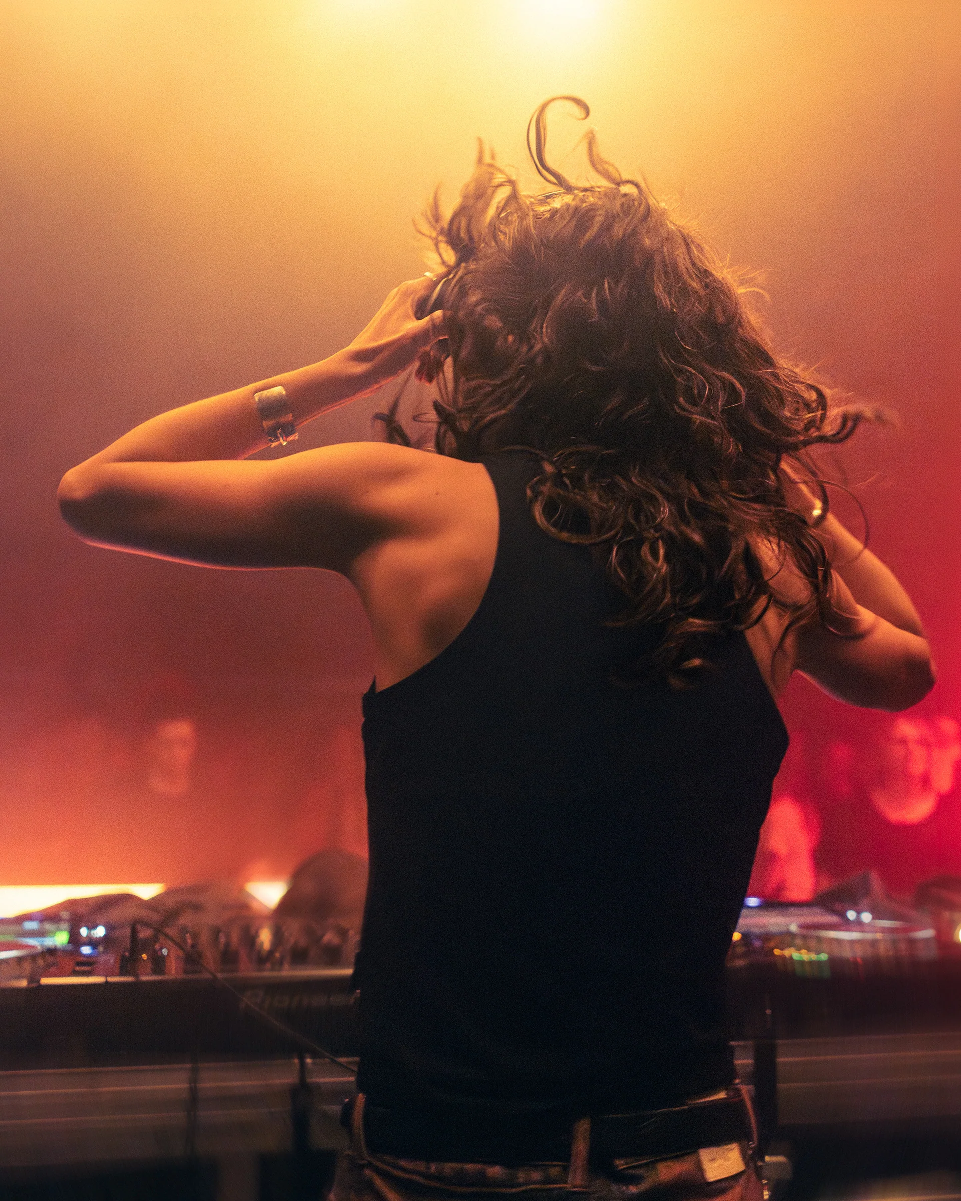 Woman dancing with her hair in motion under warm stage light.