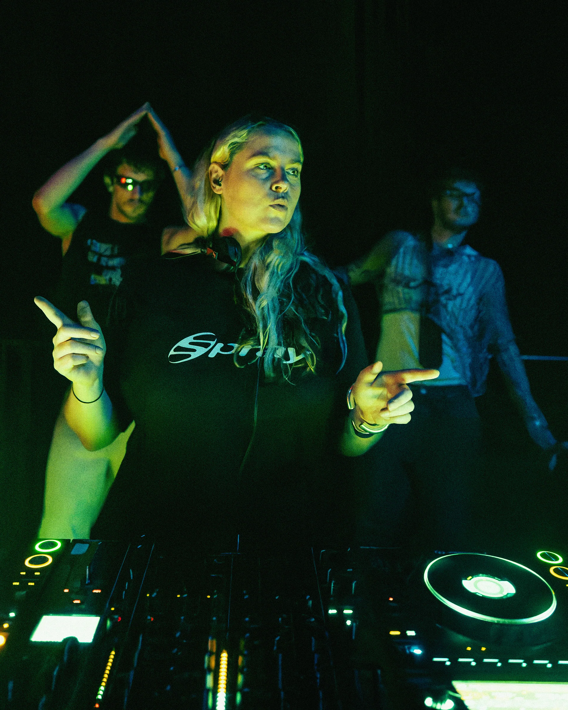 Close view of a DJ deck during a green-lit club set.