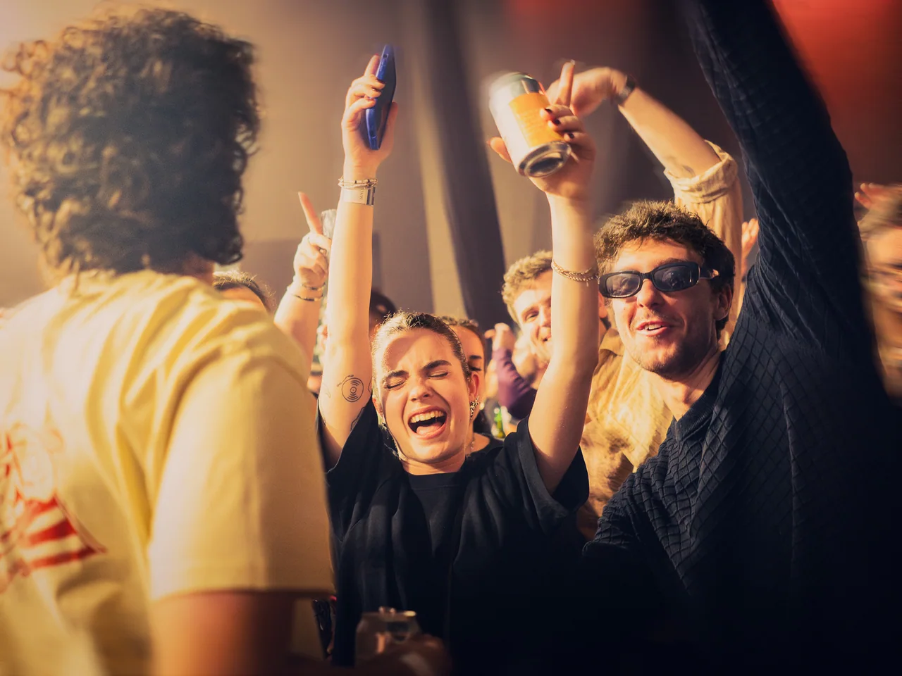 Friends cheering with their hands raised in a crowded venue.