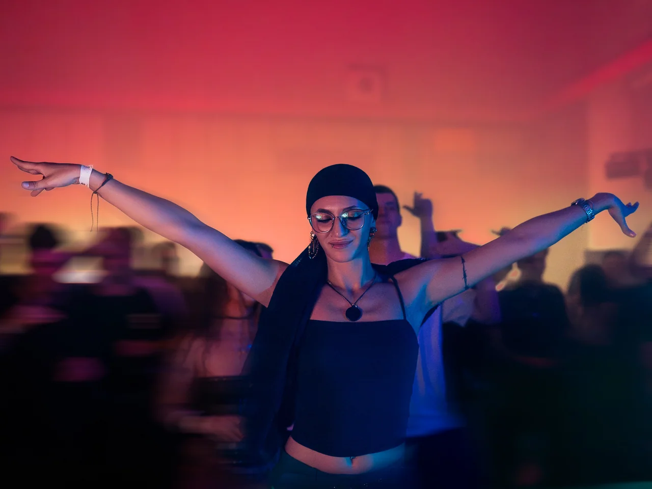 DJ silhouetted against pink light with the crowd in the foreground.