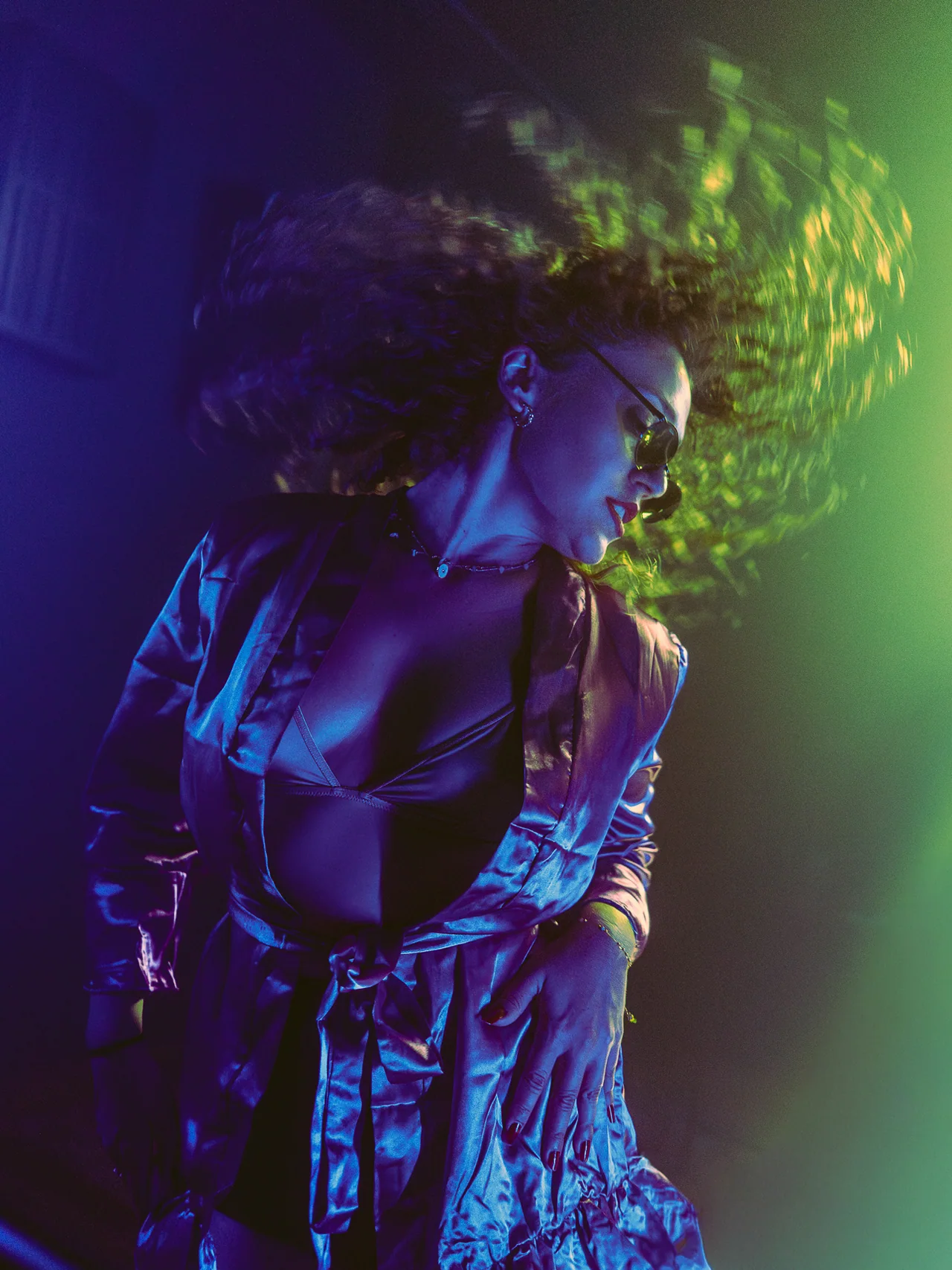 Crowd member in profile surrounded by green light and movement.