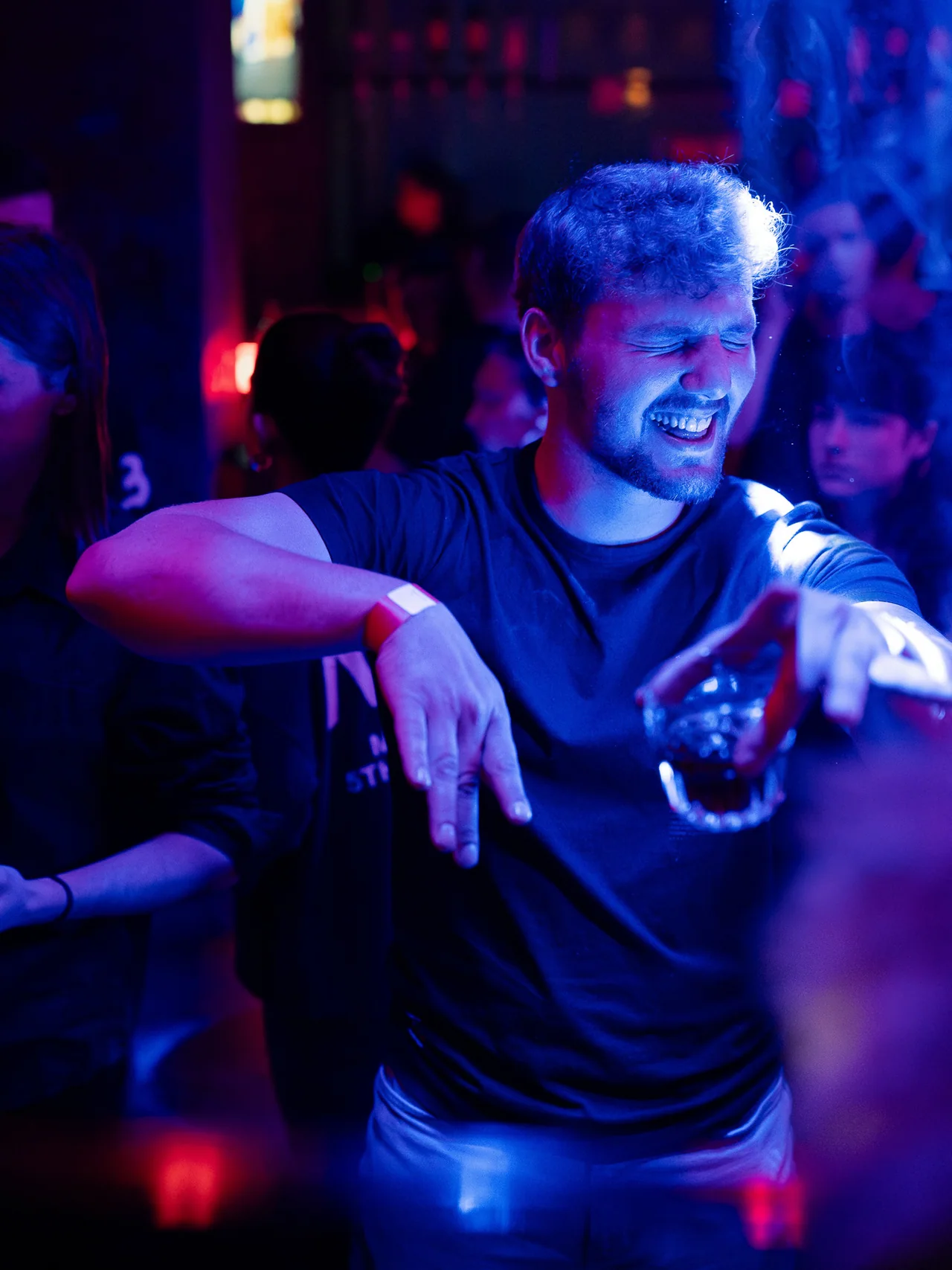 Smiling guest dancing in blue and violet club light.