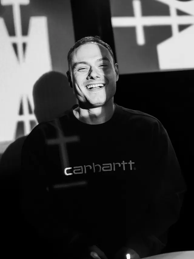Black-and-white portrait of a smiling man in front of graphic lights.