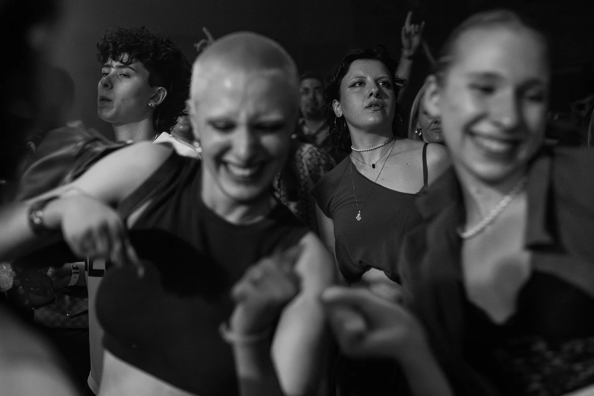 Three friends laughing together in a crowded club.