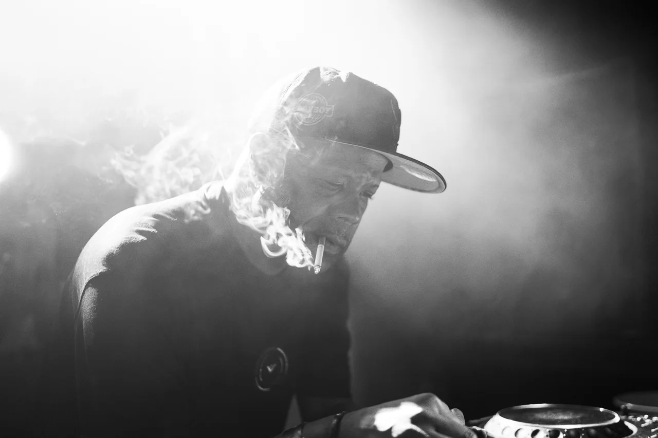 Black-and-white profile of a DJ surrounded by stage haze.