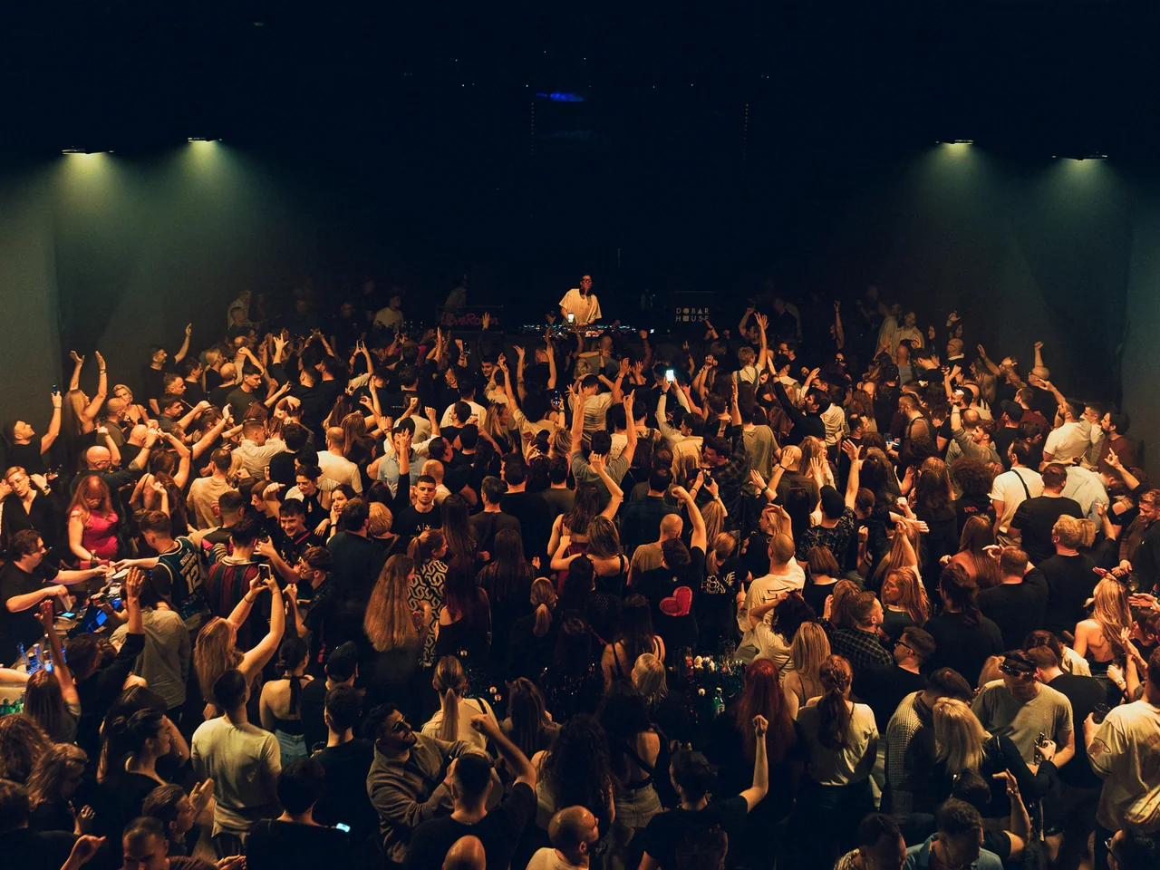 Wide view of a cheering audience inside a concert hall.