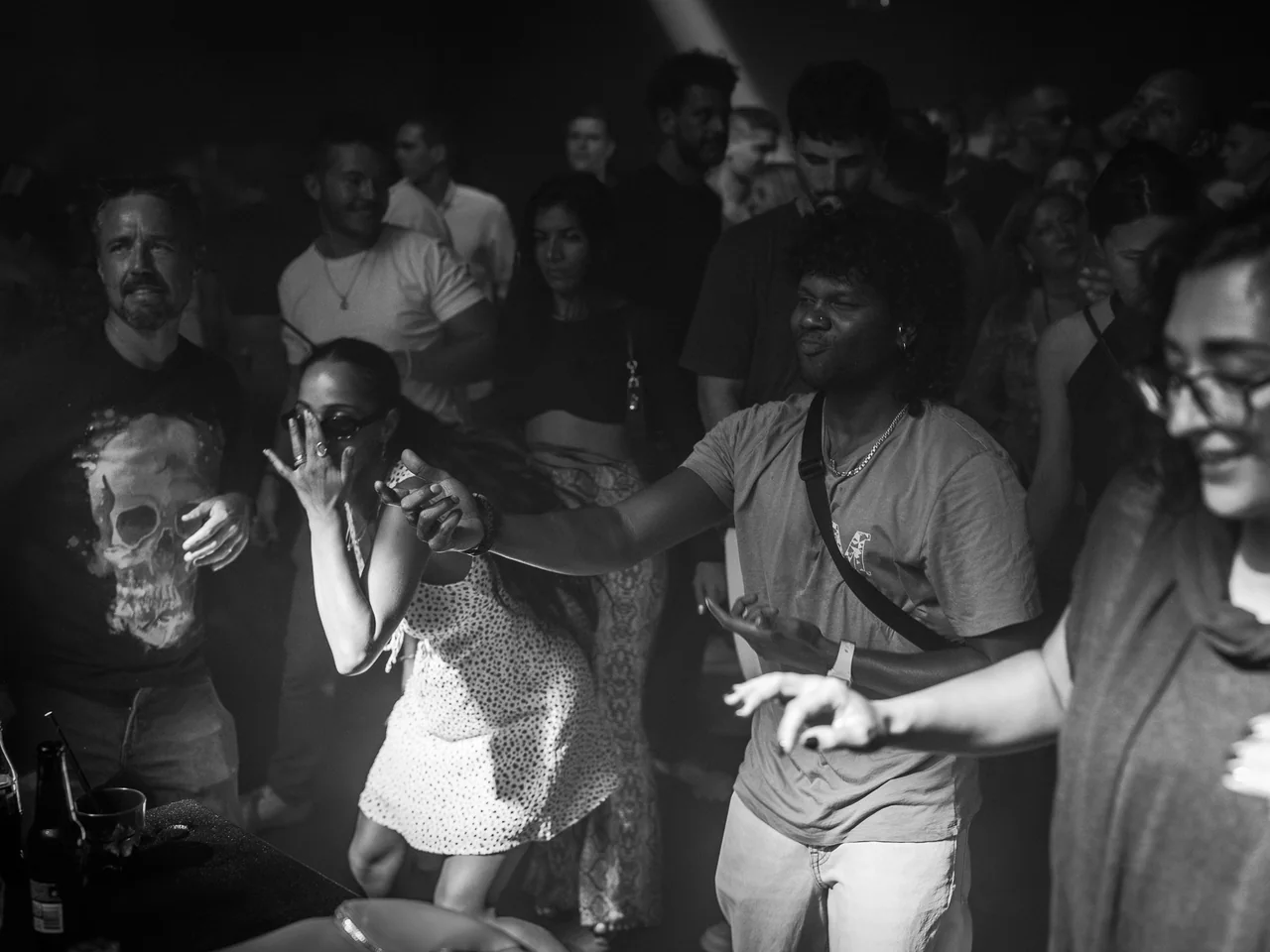 Black-and-white photograph of dancers moving through a club crowd.