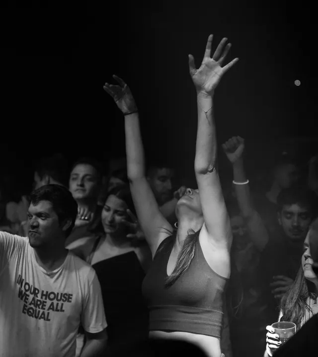 Black-and-white crowd scene with hands raised at the front row.