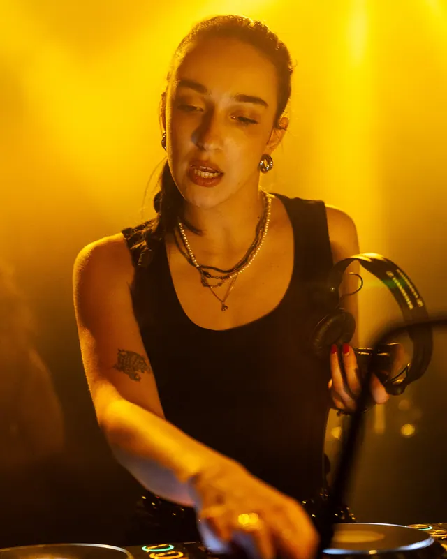 Close portrait of a woman at the booth in strong yellow light.
