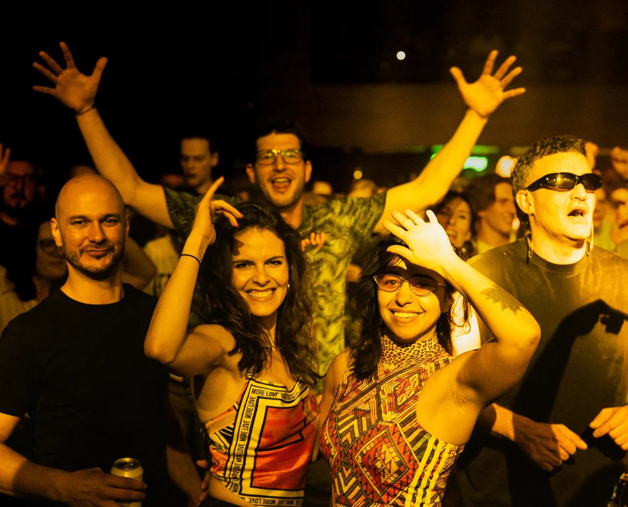 Group of friends smiling and waving directly at the camera.