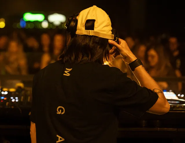 DJ photographed from behind while working at an outdoor event.