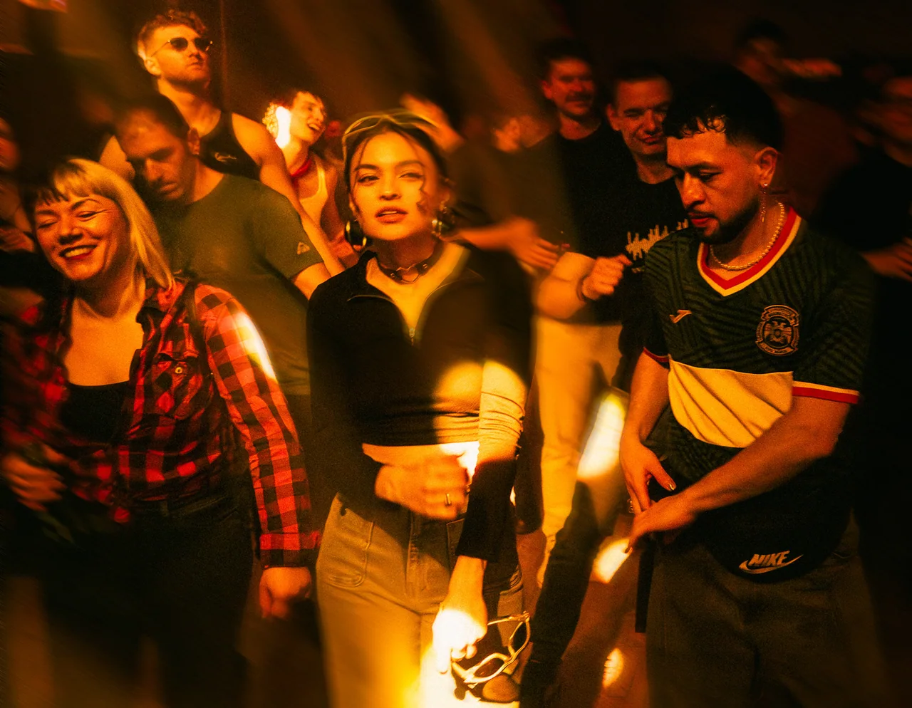 Friends dancing together in the warm light of a crowded venue.