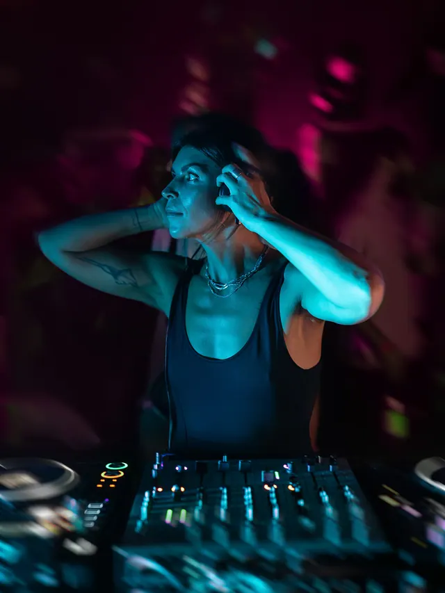 Woman dancing with both hands near her head in cool blue light.