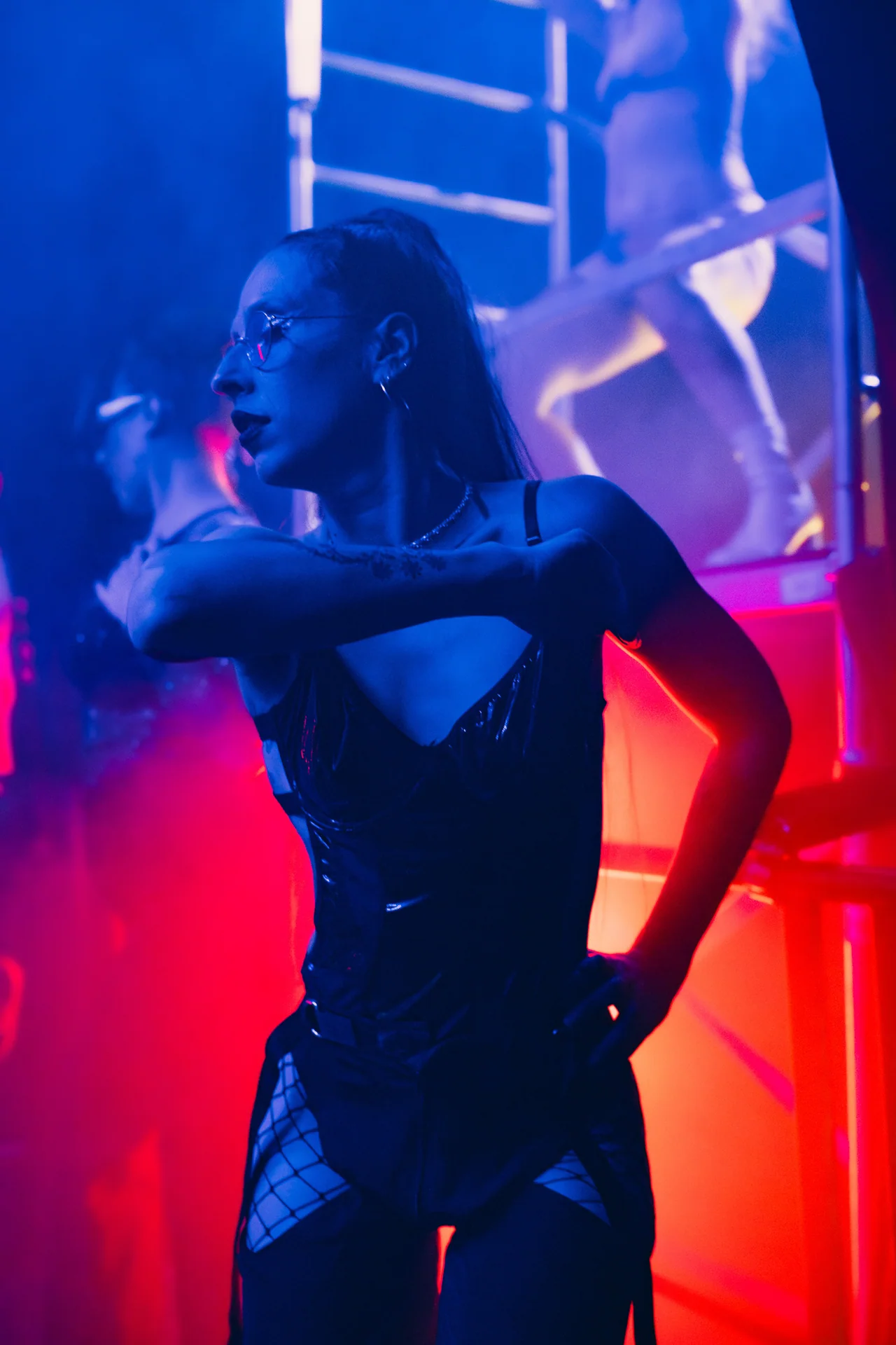 Close crop of a dancer moving through saturated blue and red light.