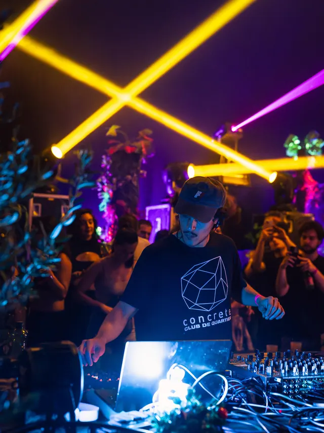 Crossed yellow and magenta beams above a dark club crowd.