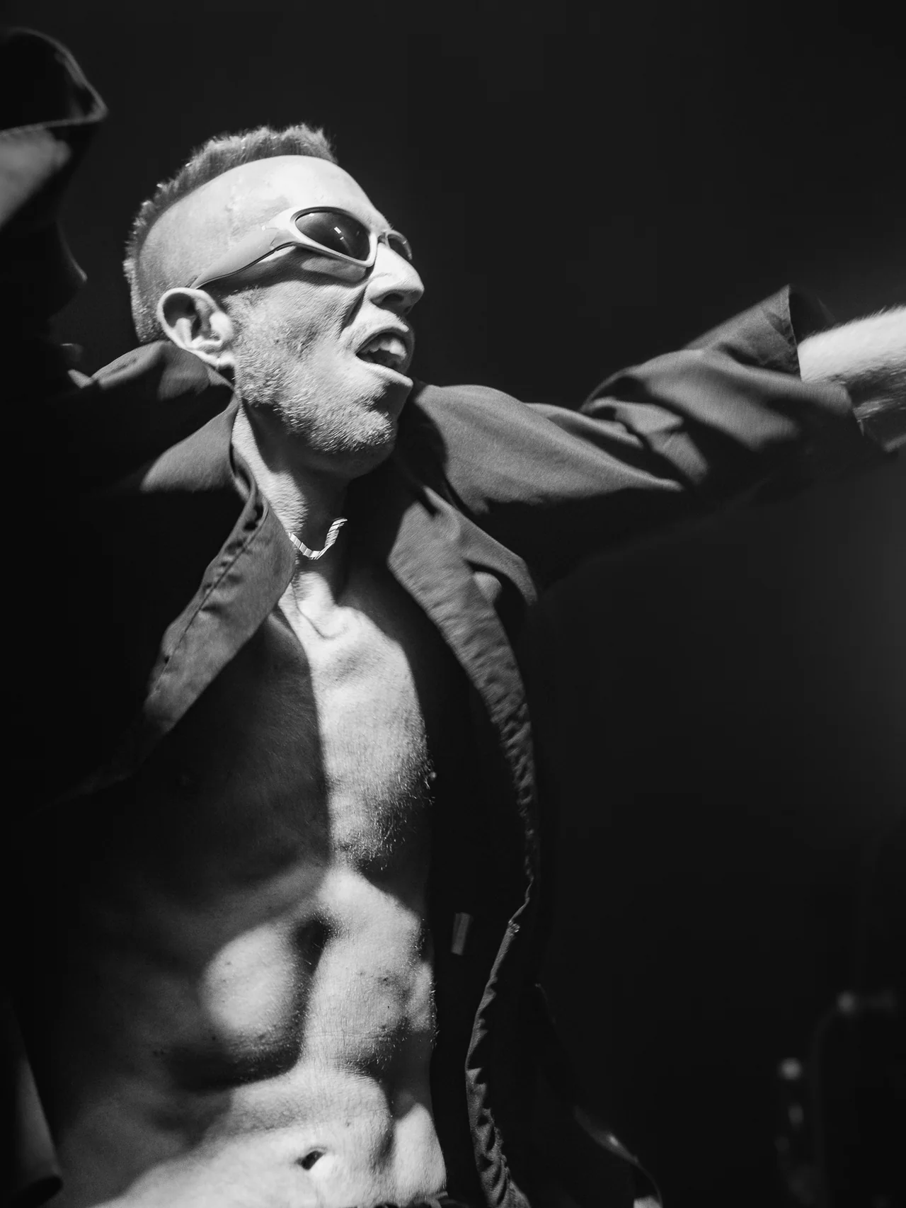 Black-and-white close portrait of a performer in sunglasses.