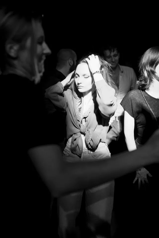 Black-and-white portrait of a woman holding her head in the crowd.