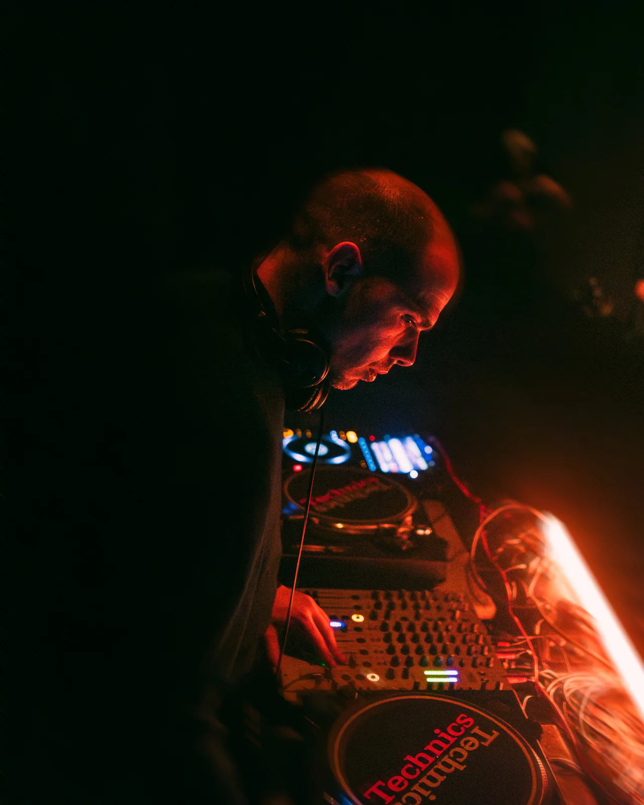 Technics turntable slipmat glowing beside a red-lit DJ mixer.