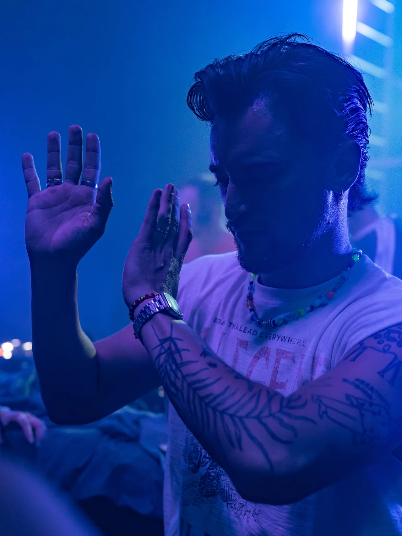 Man raising one hand in deep blue club light.
