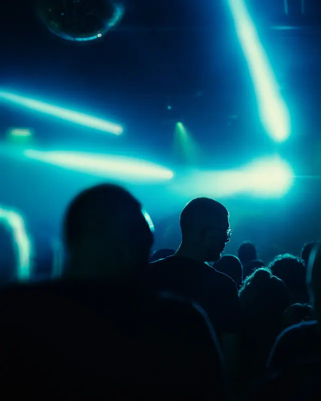 Blue stage beams cutting through haze above audience silhouettes.